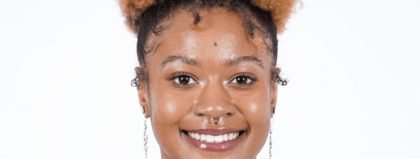 Smiling person with curly hair and earrings.